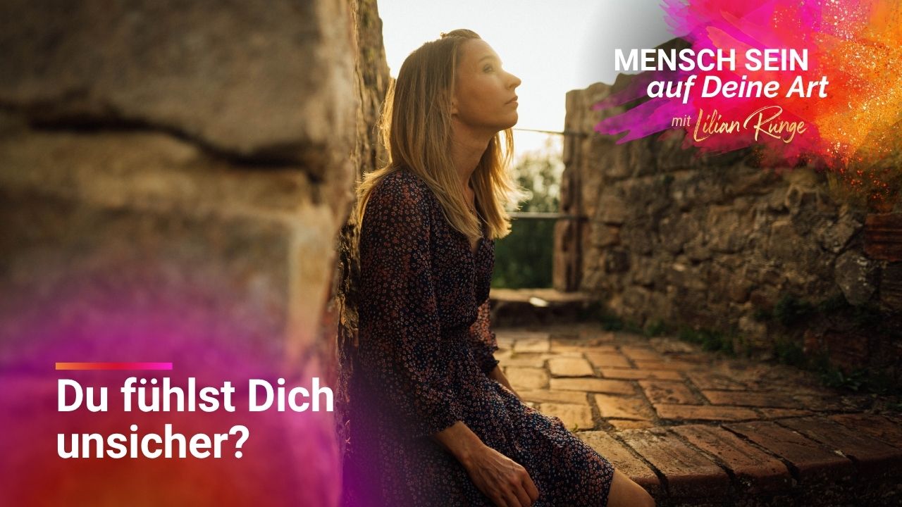 Lilian sitzt an einer Steinmauer und schaut in die Ferne